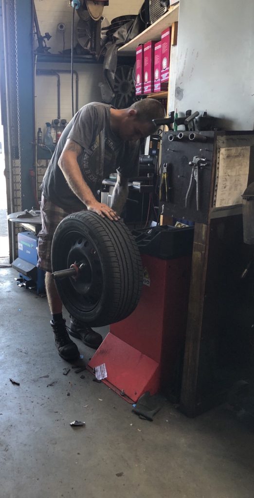 Een monteur rolt een band naar de balanceermachine