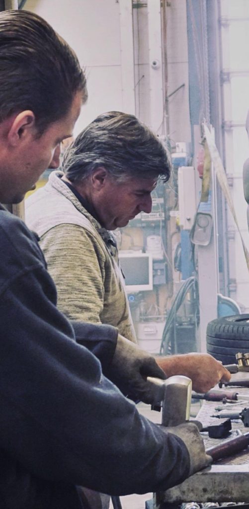 Een oudere monteur aan de werkbank, in de werkplaats van Ton's Autohal