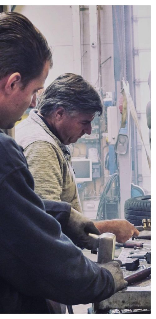 Een oudere monteur aan de werkbank, in de werkplaats van Ton's Autohal