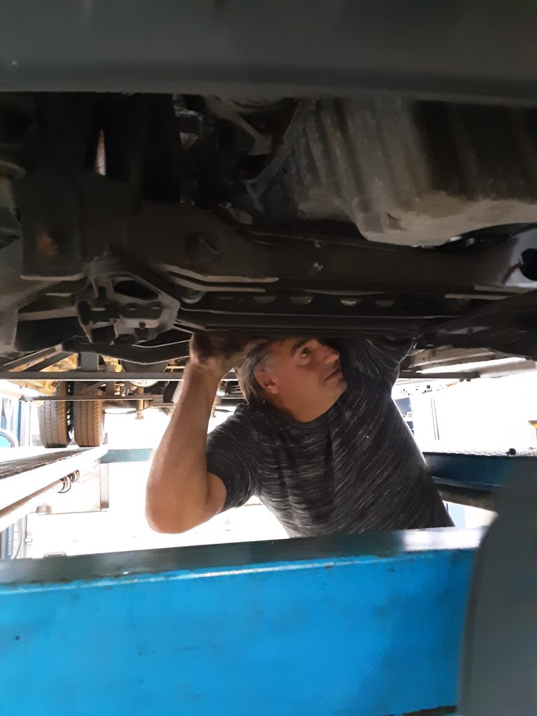 Een monteur kijkt onder een auto op de brug