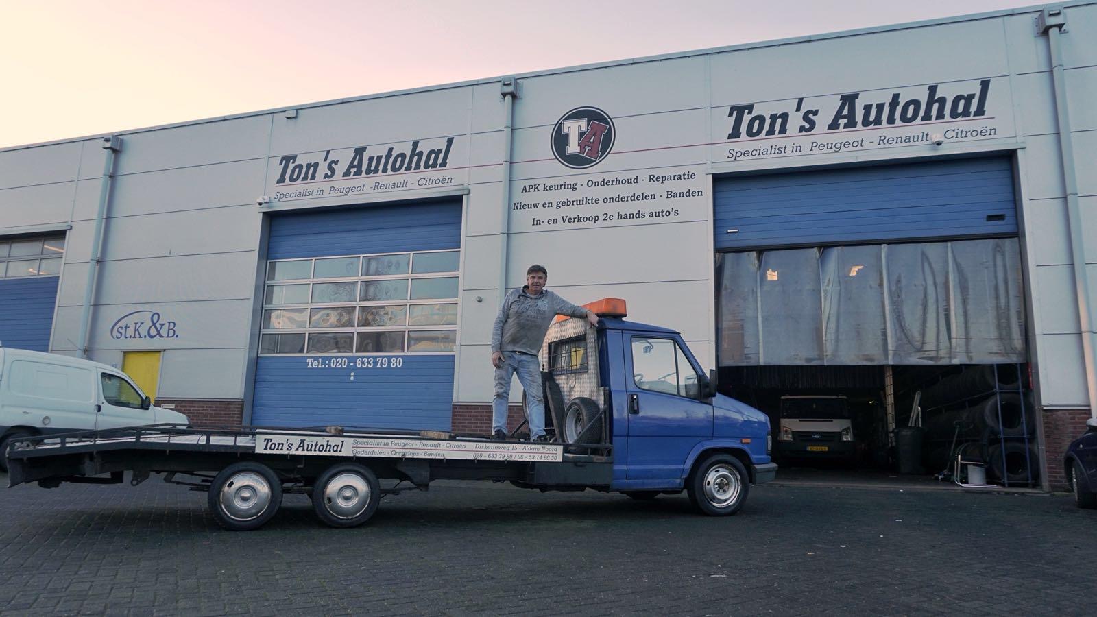 Het pand van Ton's Autohal met Ton op de oprijwagen voor de deur