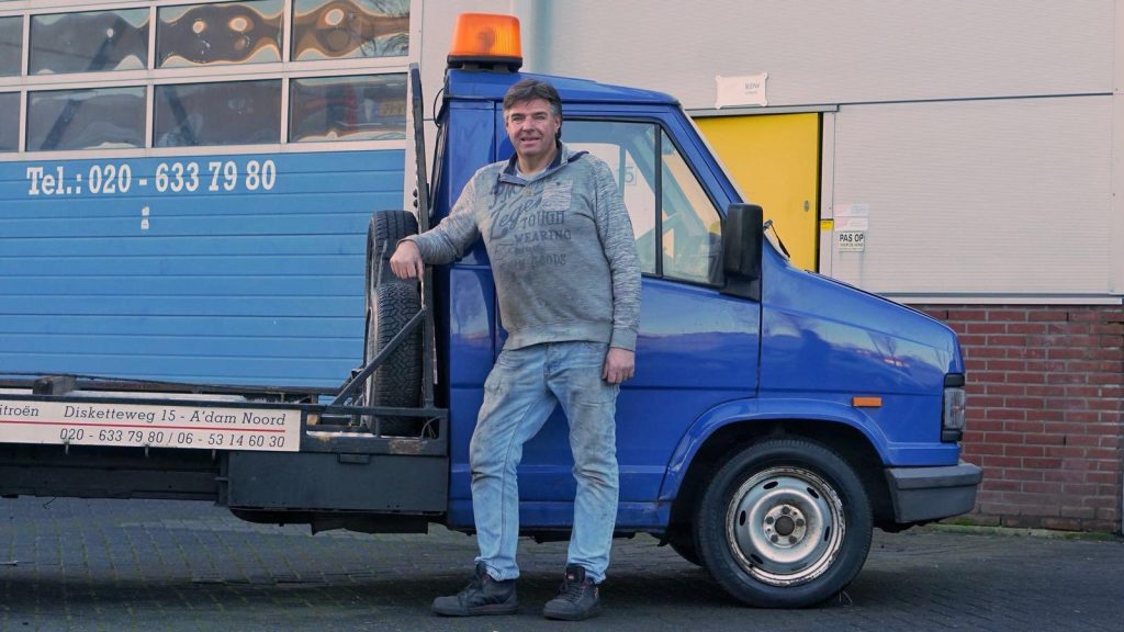 Ton staat tegen de blauwe oprijwagen voor het pand aan de Disketteweg