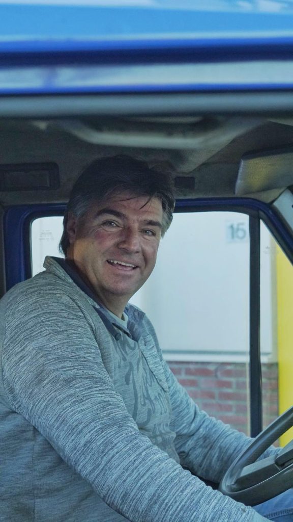 Ton lacht vanuit de cabine van de oprijwagen